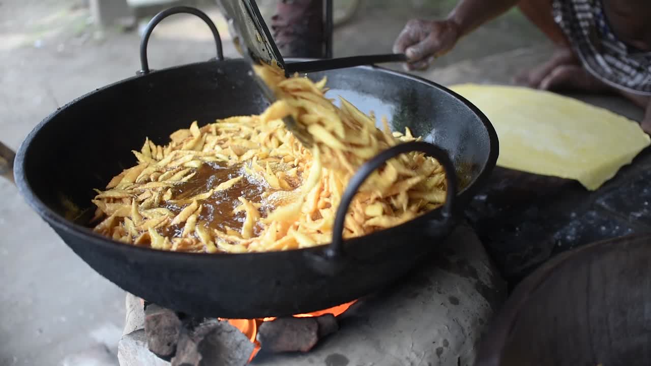 A man using mesh skimmer to fry Indian street snacks at a fair, SLOW MOTION