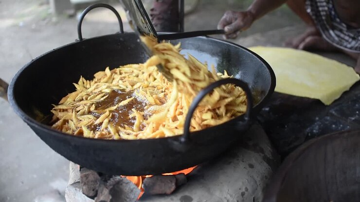 A man using mesh skimmer to fry Indian street snacks at a fair, SLOW MOTION
