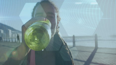 hexagonal shapes against african american woman drinking water on promenade