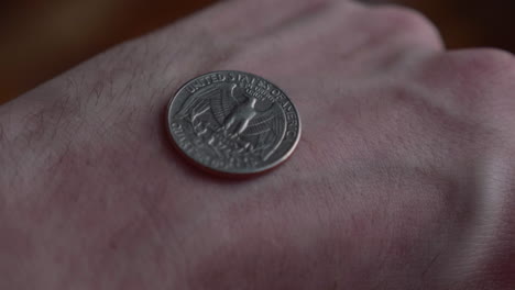 revealing quarter dollar coin tossed at the back of a hand with tail facing up