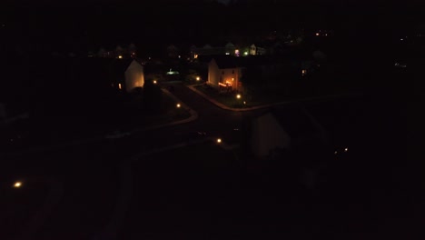 warm glowing houses and lights of lantern in quiet american residential area at night. aerial approaching shot.