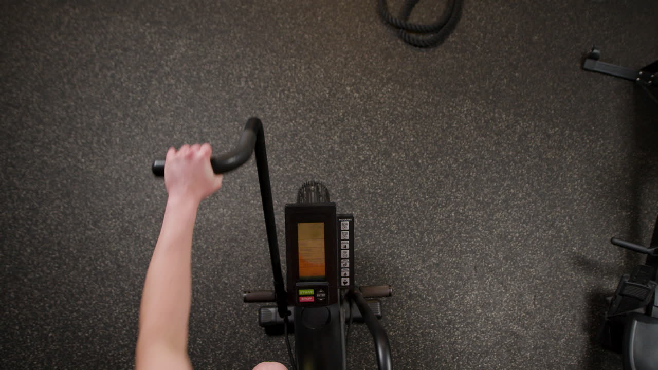 체육관 에서 정지 된 자전거 를 타고 운동 하는 여자