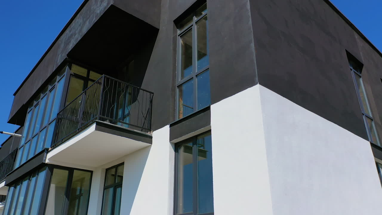Tall black and white architecture. Modern facade of new residential building with balconies. Camera moves top down.