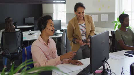 Two-diverse-businesswoman-discussing-work-at-desk-computer