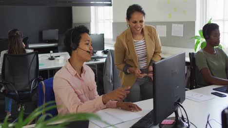 dos mujeres de negocios diversas discutiendo el trabajo en la computadora de escritorio
