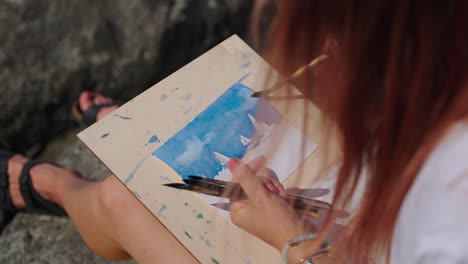 woman painting watercolor seascape outdoors