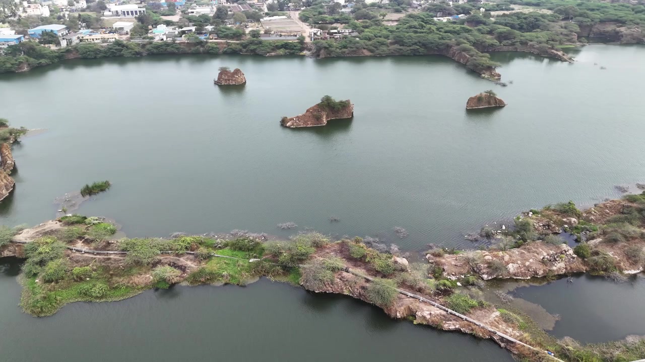 Ripresa aerea con drone della cava di granito abbandonata di Sikkarayapuram che mostra laghi di cava color smeraldo, affioramenti rocciosi, stretti ponti di terra e vegetazione lussureggiante, creando un paesaggio geologico unico vicino a Chennai.