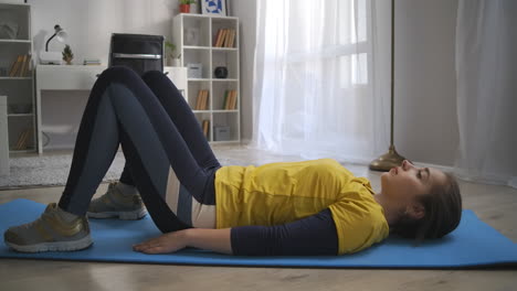 morning workout at home teen girl is training alone in living room lying on floor and lifting hips tensing abdominal and back muscles healthy lifestyle