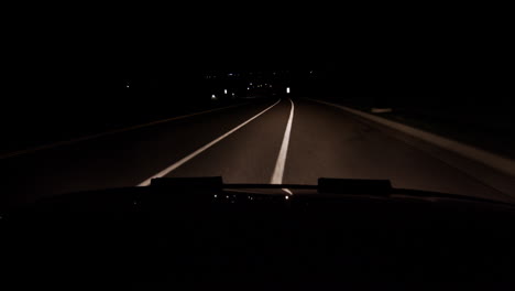 a hood of a car point of view driving at night starting the car and pulling back onto the highway or road or street