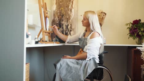 a cute fair-haired girl in a wheelchair draws on the glass