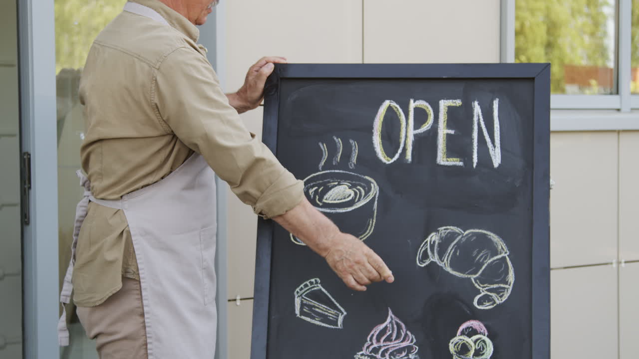 Slowmo of Baker Writing on Advertisement Chalkboard