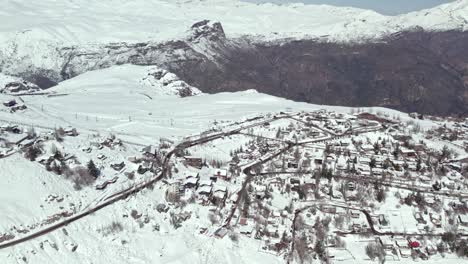 aerial view flying over snow covered farellones ski resort village neighbourhood in the andes mountains, santiago, chile