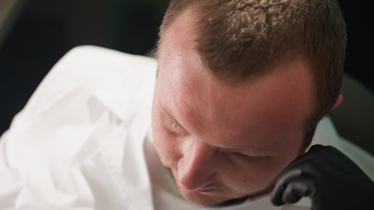 그가 머리에 손을 고 잠을 자는 동안 기술자의 얼굴을 근접적으로 볼 수 있습니다.