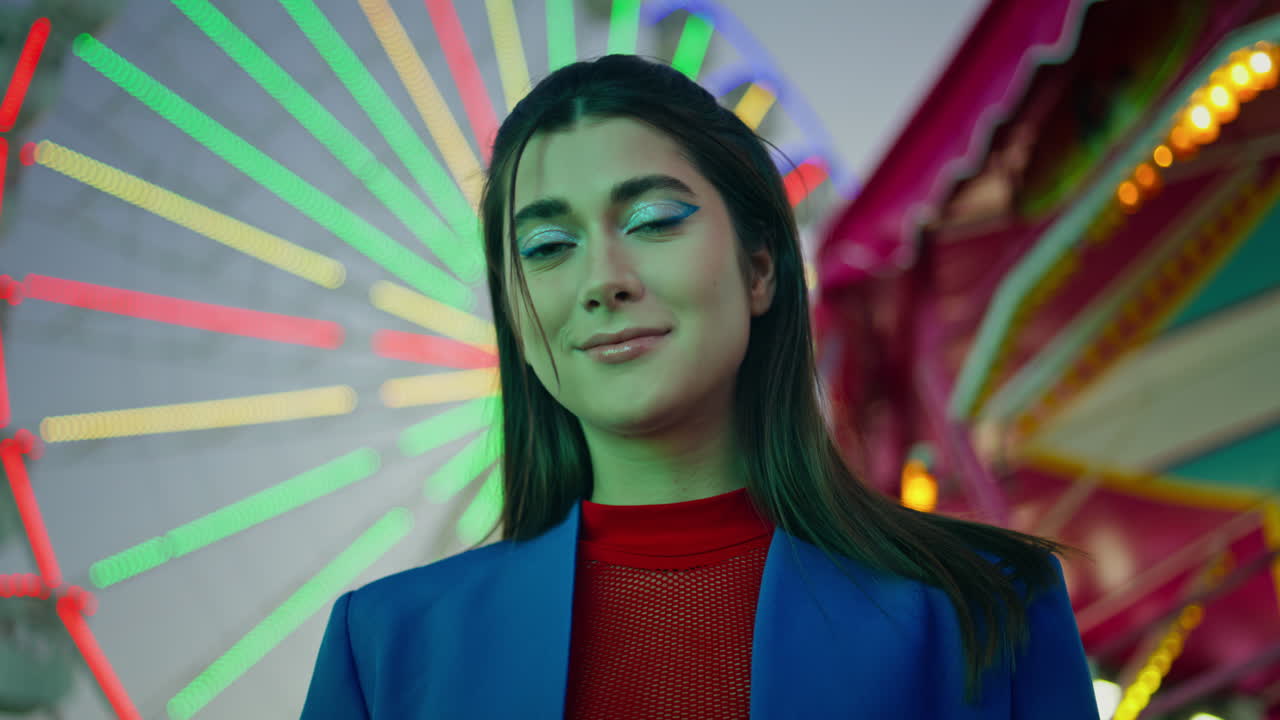 Smiling girl posing ferris wheel in illuminated luna park closeup. Model rest