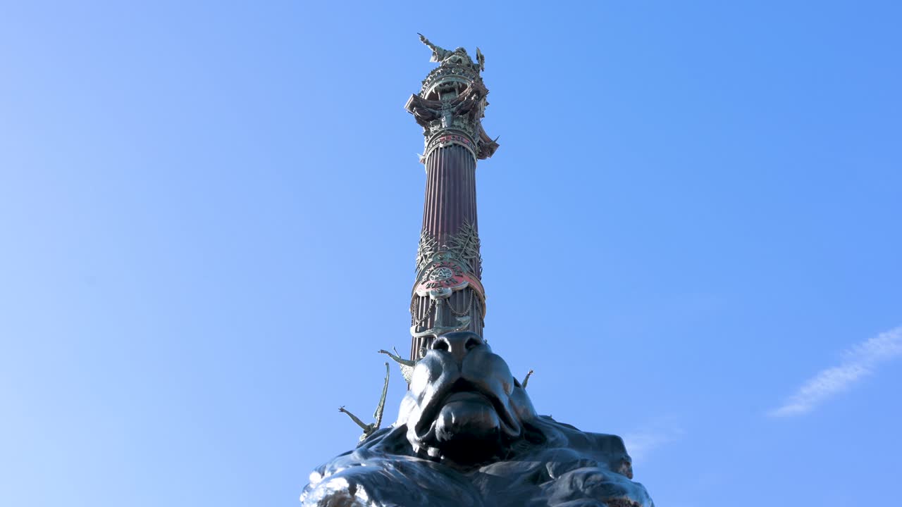 The historic statue of Christopher Columbus stands atop its ornate column against a clear blue sky in Barcelona. A famous city landmark, it commemorates the explorer's first voyage to the New World