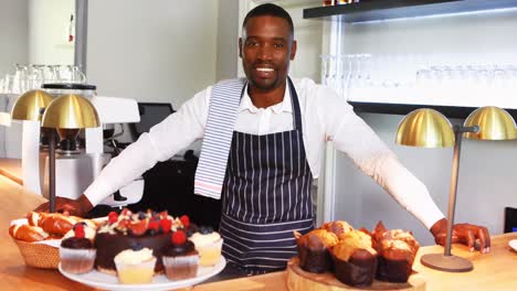 portrait of smiling waiter standing counter