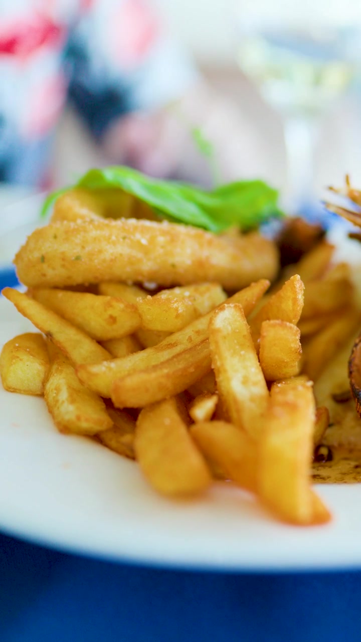 Golden fried fish and chips on plate, shallow depth of field, restaurant setting, natural lighting