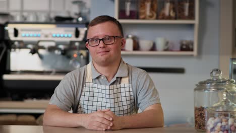 portrait of caucasian man with down syndrome working in the cafe.