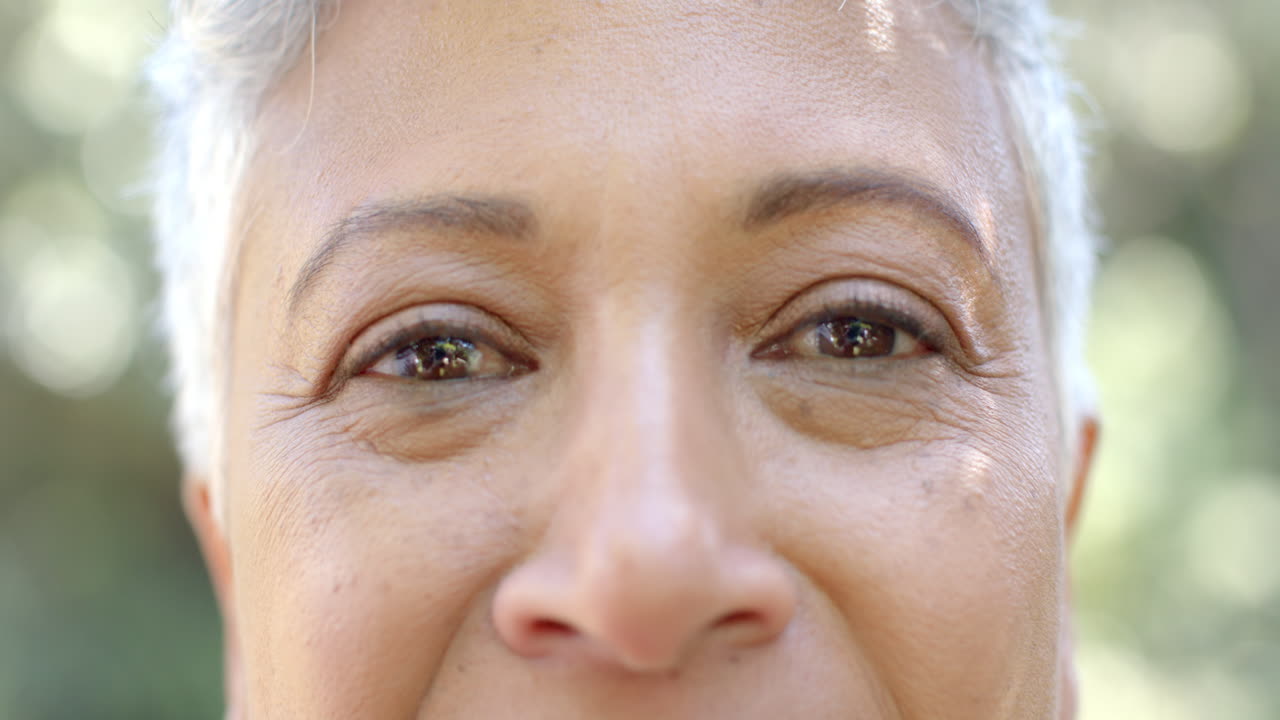 retrato de una feliz mujer biracial con cabello corto en un jardín soleado en casa, en cámara lenta