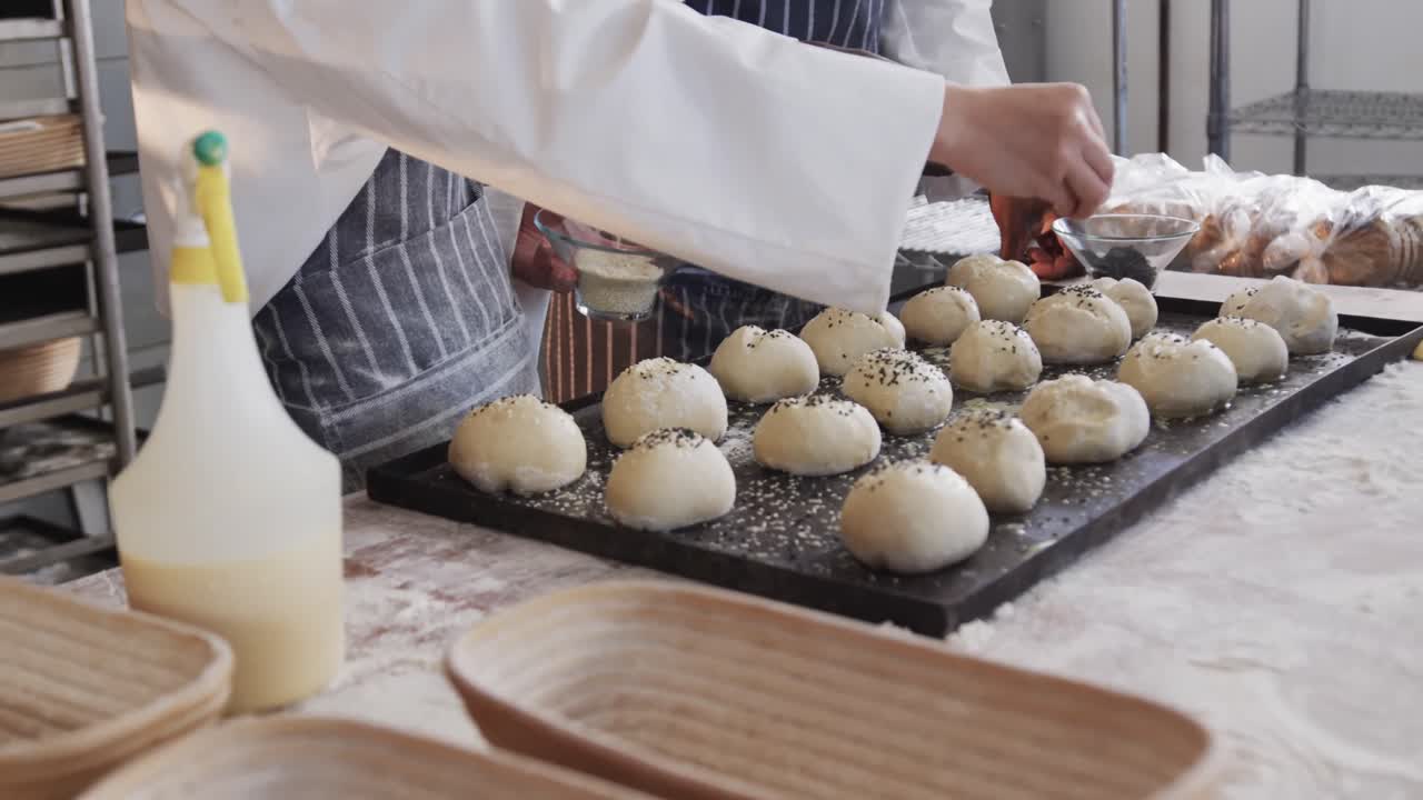 diversos panaderos trabajando en la cocina de la panadería, rociando semillas de amapola en rollos en cámara lenta