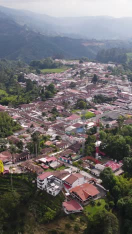 drone shot capturing the vibrant cityscape of salento nestled amidst the verdant landscapes of colombia. vertical video