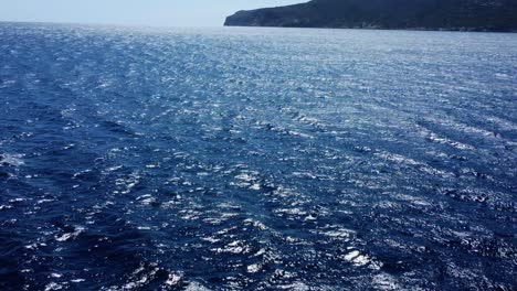 drone speeding over waves and blue water towards an island in the sun in spain mallorca