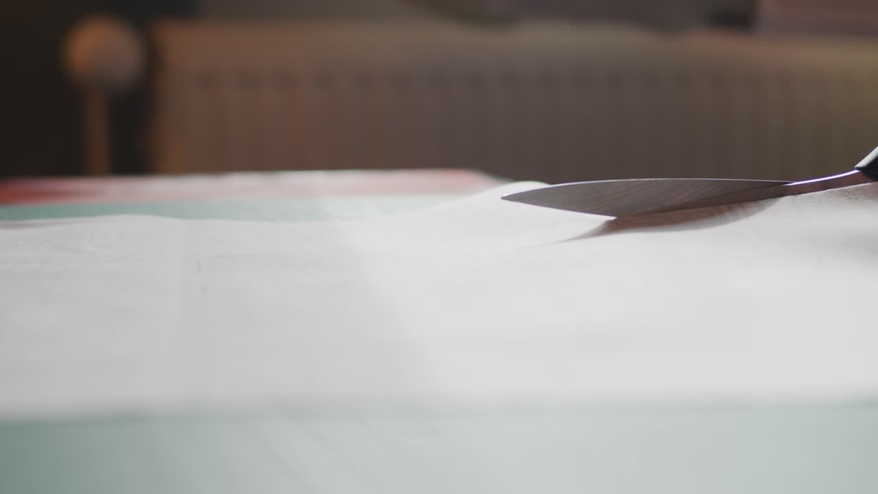 Scissors cutting through fabric on a table slowly