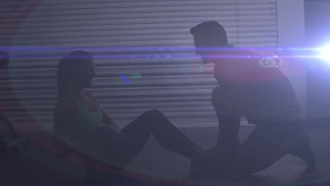 Animation-of-man-and-woman-exercising-together-in-gym-with-blue-light-in-the-foreground