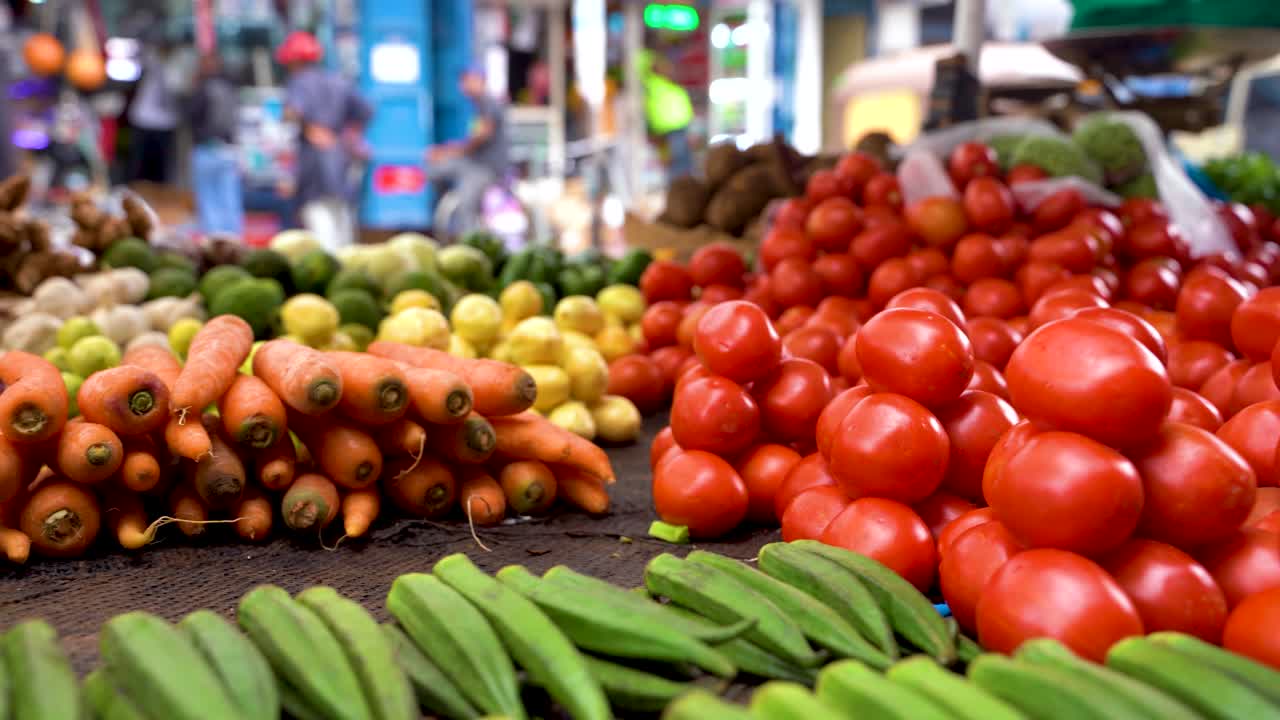 Uma panorâmica de tomates, cenouras e pepinos em uma quitanda de rua.