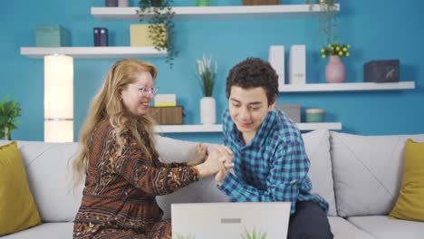y concentrado madre hijo mirando a la computadora portátil serio concentrado en casa y regocijándose con buenas noticias.