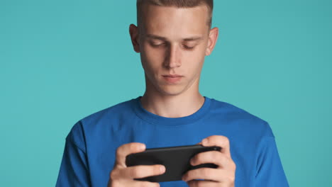 young blond guy playing with his smartphone