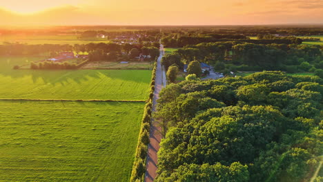 Sunset over rural road. A vibrant sunset casts warm light over a winding road surrounded by lush greenery and distant village structures