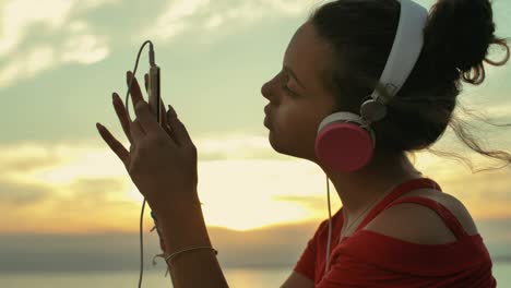 teenager girl with headphones listening music on the beach. shot in slow motion