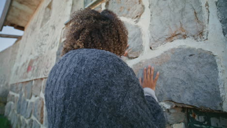 crying woman touching wall suffering alone near mediterranean castle closeup
