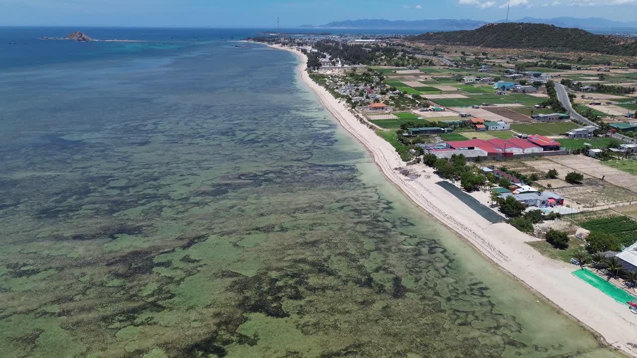 Aerial forward movement over "My Hoa" Lagoon in Phan Rang, Vietnam, capturing the pristine waters and coastal village.