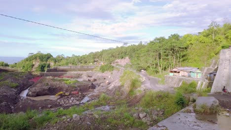 Aerial-view-of-traffic-on-narrow-road-beside-sand-mine-with-working-industrial-excavator---Indonesia,Asia