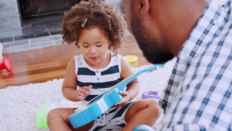 young black girl playing ukulele and singing with her dad