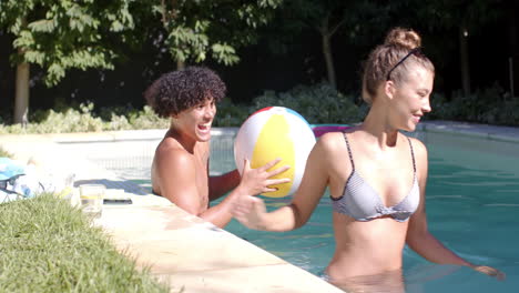 man relaxing in pool, playing with colorful beach ball on sunny day, copy space