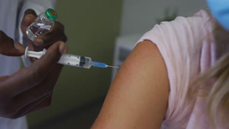 caucasian female patient wearing face mask sitting in hospital bed getting injection