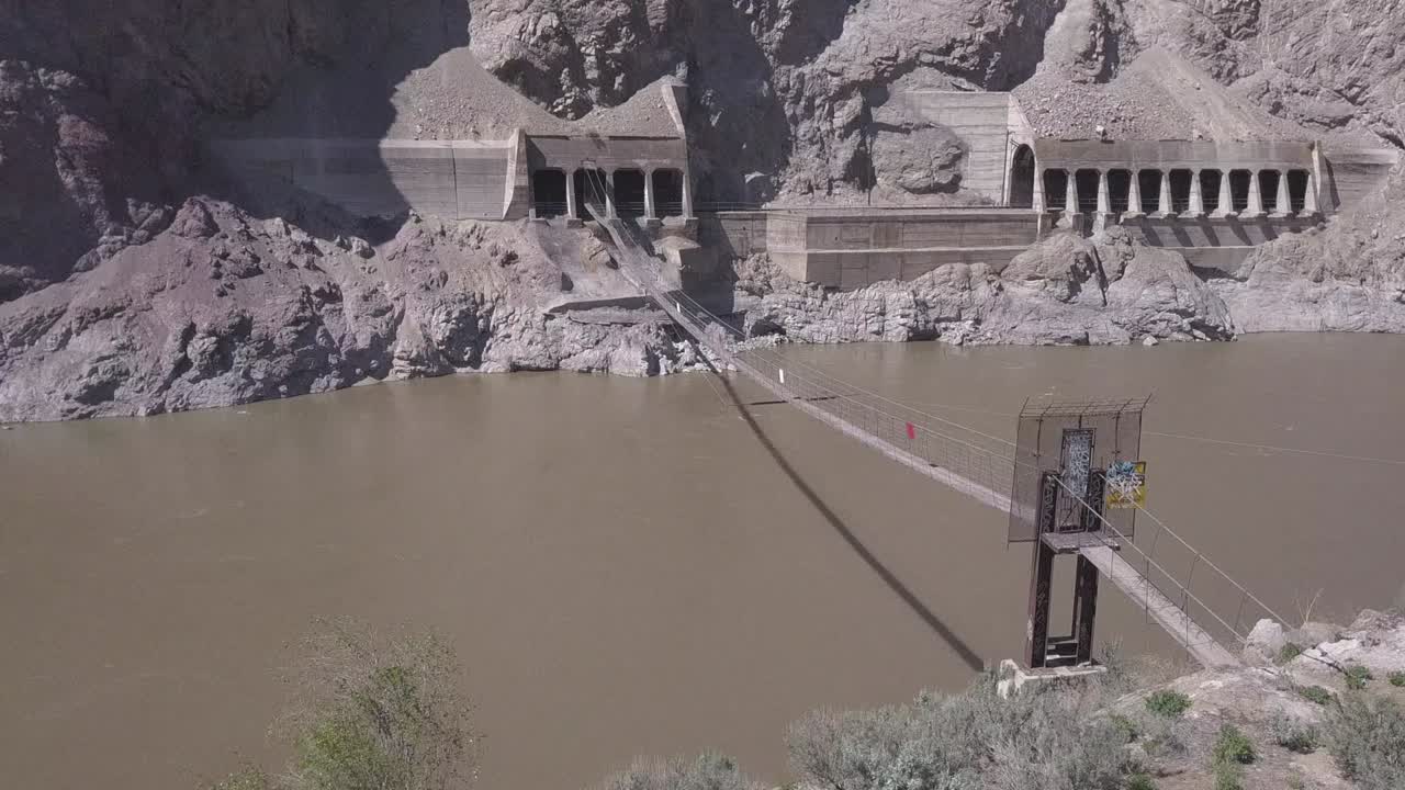 Private suspension walking bridge over river canyon to railway tunnel