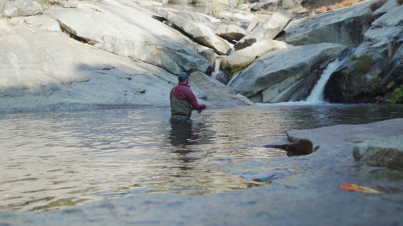 tiro estático, hombre pesca con mosca en aguas profundas de la cintura en el desfiladero de granito