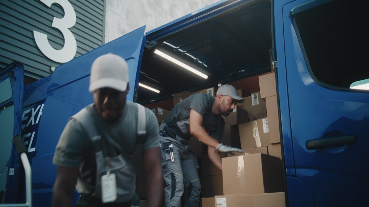 Two Delivery Workers Loading Parcels into a Blue Van