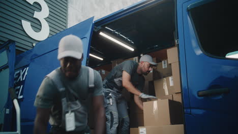 two delivery workers loading parcels into a blue van
