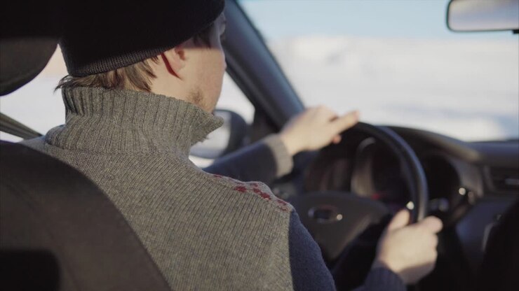 Uomo che guida un'auto in inverno