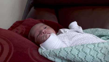 Neugeborener-Junge,-Der-Auf-Dem-Sofa-Liegt-Und-Die-Arme-Bewegt-Und-Gähnt