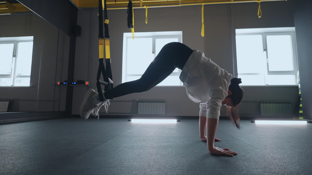 fitness TRX training exercises at gym woman push-up workout. Attractive woman doing exercise for hands in gym. core abs crossfit oblique training with fitness straps in the gym's studio. TRX