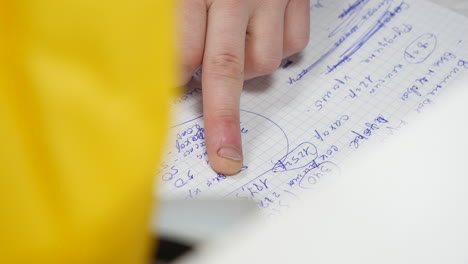 persona que señala notas escritas a mano en un bloc de notas