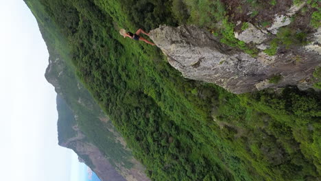 beautiful blonde girl climbing high ridges cliff on the coast of madeira island, portugal