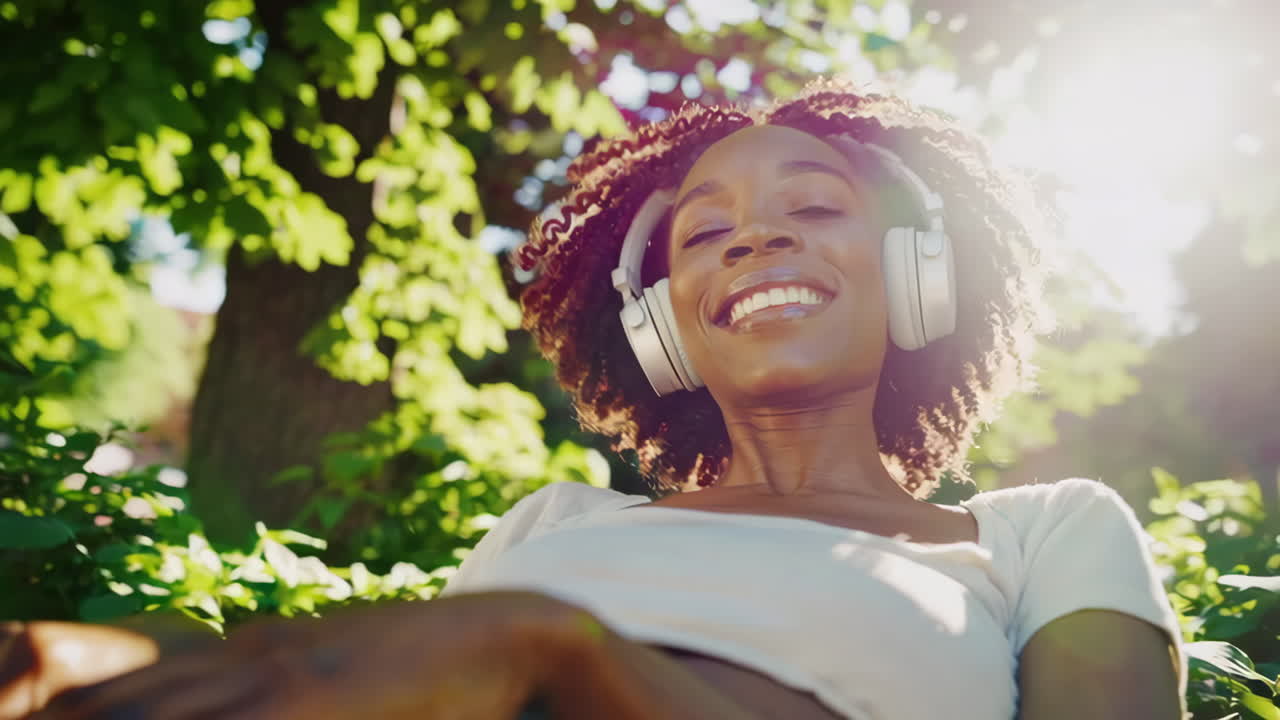 Young Woman Enjoying Music with Headphones in a Sunny Park