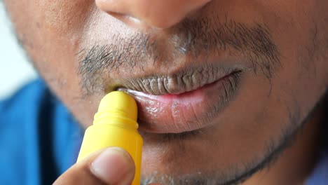 applying lip balm to a man's lips